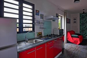 una cucina con armadi rossi, lavandino e finestra di JASMIN DE NUIT - Villa FOURNAISE a Le Tampon