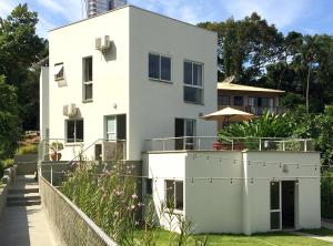 a white house with a fence in front of it at Vila Praiana in Ubatuba