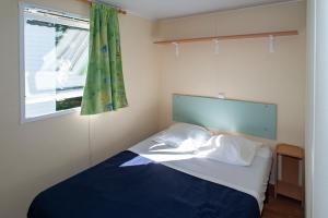 a bed in a room with a window and a bed sidx sidx sidx at Camping du Bournat in Le Bugue