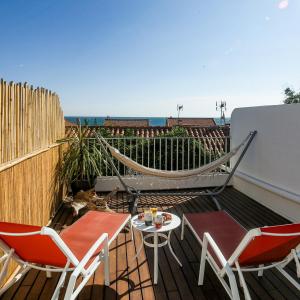 eine Terrasse mit Stühlen und einer Hängematte auf dem Balkon in der Unterkunft Le Fanal in Argelès-sur-Mer