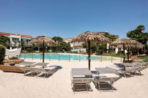 - un groupe de chaises longues et de parasols sur la plage dans l'établissement Villa Carlotta Jesolo Lido, à Lido di Jesolo