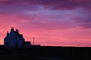 a silhouette of a house with a sunset in the background at Kirkapol Beach Apartment in Middleton