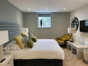 a bedroom with a large white bed and a desk at La Pulente Cottages in St Brelade