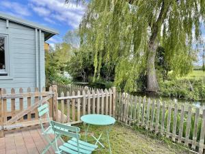 a table and chairs in front of a fence at Willow Tree Lodge - Cosy lodge in the heart of the Kent countryside in Littlebourne