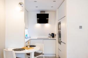 una pequeña cocina blanca con mesa blanca y sillas en Le Cwtch - Beautiful 1 bed boutique apartment en Cardiff
