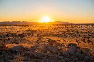 a sunset in the desert with a rock wall at Camp Gecko - PRIVATE NATURE RESERVE; TENTED CAMP AND CAMPSITE in Solitaire