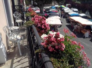 a balcony with tables and flowers on a street at La Maison de la Riviere B&B in Espéraza
