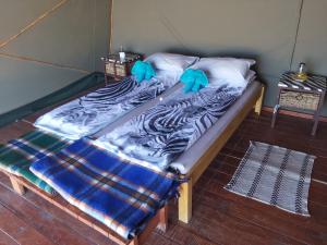 a bed in a room with two blue pillows on it at Camp Gecko - PRIVATE NATURE RESERVE; TENTED CAMP AND CAMPSITE in Solitaire