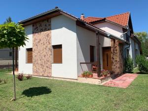 a small white house with a grass yard at László Nyaralóház in Balatonfenyves
