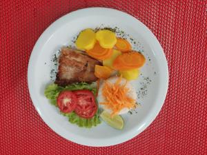 a plate of food with meat and vegetables on a table at Toulouse Motel (Adult Only) in Natal +15 photos
