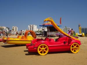 um carro vermelho e um barco amarelo na praia em Apartamento T1 com Piscina e Vista mar - PRAIA DA ROCHA Portimão em Portimão