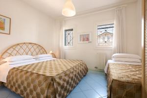 a bedroom with two beds and two windows at Villa Carlotta Jesolo Lido in Lido di Jesolo