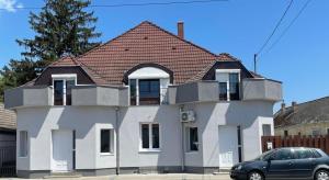 ein weißes Haus mit braunem Dach in der Unterkunft Lelle Centrum Vendégház in Balatonlelle