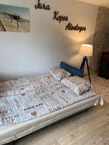 a bedroom with a bed with a sign on the wall at Taikos 3 studio in Nida