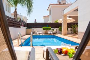 a table with a plate of fruit next to a swimming pool at Villa Danata in Protaras