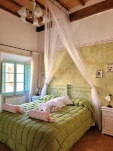 a bedroom with a green bed with curtains on it at Residenza storica il Pozzo in San Quirico dʼOrcia