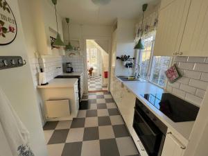 a kitchen with a checkered floor and white cabinets at Tutviksvägen 35 in Vendelsö