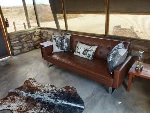 a brown leather couch in a room with a view at Camp Gecko - PRIVATE NATURE RESERVE; TENTED CAMP AND CAMPSITE in Solitaire