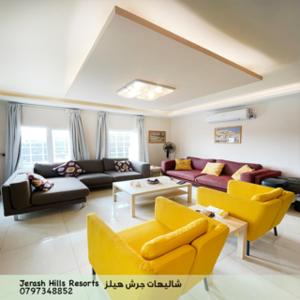 a living room with yellow chairs and a couch at Jerash Hills Farm & Chalets in Jerash