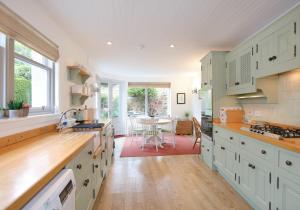 a kitchen with white cabinets and a table at Primrose Cottage in Gullane