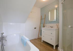 a bathroom with a white tub and a sink and a mirror at Primrose Cottage in Gullane +18 photos