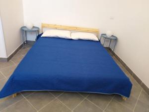 ein blaues Bett in einem Zimmer mit 2 Tischen in der Unterkunft LA Casina di Anna in Menfi