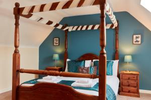 a bedroom with a canopy bed with blue walls at Finest Retreats - Willow Barn in Ashbourne