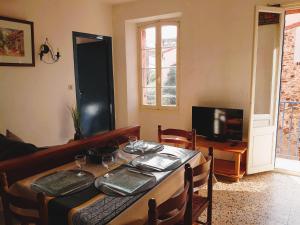 ein Esszimmer mit einem Tisch und einem TV in der Unterkunft 5COMA2 Appartement proche plage in Collioure