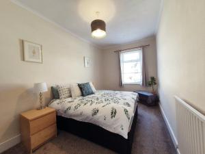 a bedroom with a bed and a window at Brodie's Hideaway: Stylish two-bed Amble apartment in Amble