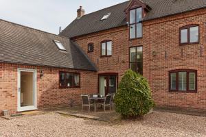 a brick house with a table and chairs in the courtyard at Finest Retreats - Willow Barn in Ashbourne