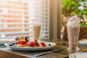 a plate of waffles with strawberries and blueberries next to two drinks at The Maynard in Scarborough