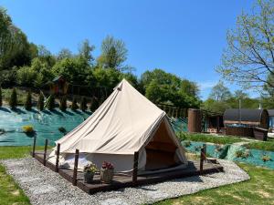 duży biały namiot na podwórzu obok rzeki w obiekcie Glamping Bieszczady z basenem w Solinie