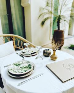 un tavolo bianco con piatti e bicchieri da vino sopra di Riad Alia a Marrakech