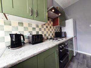 a kitchen with green cabinets and a counter top at Brodie's Hideaway: Stylish two-bed Amble apartment in Amble