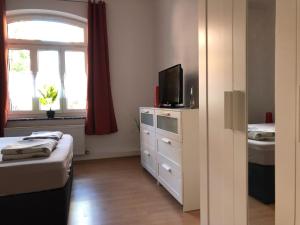 ein Schlafzimmer mit einem Bett und einem TV auf einer Kommode in der Unterkunft City Quartier Jena in Jena
