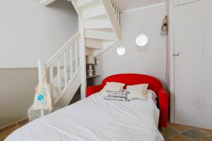 a red bed in a room with a staircase at Maison de village Casserone pour 4 personnes in Ars-en-Ré