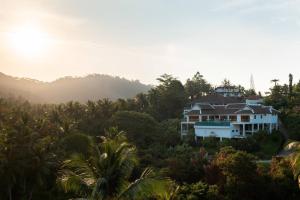 a house in the middle of a forest with the sun setting at Villa E in Taling Ngam Beach