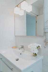 a bathroom sink with a mirror and a vase of flowers at Beachfront Bella Horizonte 5 in Savaneta