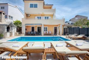 a villa with a swimming pool and a house at Vacation house with heated swimming pool 70 meters from the beach-Bobanac in Ražanj