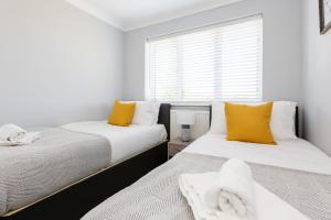 1 dormitorio con 2 camas con almohadas amarillas y ventana en Curlew - 3 Bedrooms Wi-Fi, Parking, Contractors, en Thornton