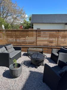 une terrasse avec des chaises, un foyer extérieur et une clôture dans l'établissement Cosy compact living with gym access., à Heberg