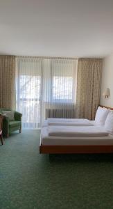 ein Schlafzimmer mit einem Bett, einem Sofa und Fenstern in der Unterkunft Hotel Kurpfalzstuben in Mannheim