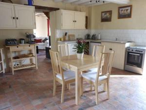 uma cozinha com uma mesa e cadeiras de madeira e uma cozinha com um fogão em Closerie Les Roches - Charming and spacious 2 bedroom cottage em Bouillé-Loretz