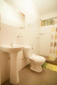 La salle de bains blanche est pourvue de toilettes et d'un lavabo. dans l'établissement Country Club Eco Casajardin, à Moyobamba