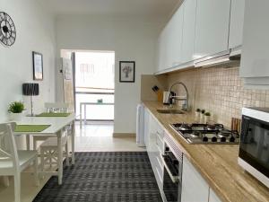 uma cozinha com armários brancos, uma mesa e um fogão em Blue Sky apartment Marina em Lagos