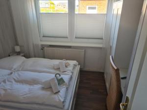 Cama pequeña en habitación con 2 ventanas en Budget en Westerland