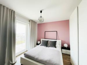 1 dormitorio con cama blanca y pared rosa en SAN APARTMENT 16th floor, en Gdansk