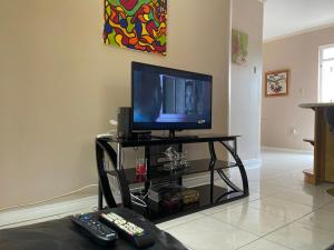 sala de estar con TV y 2 mandos a distancia en Kingstons Finest - Centrally Elegant, en Kingston