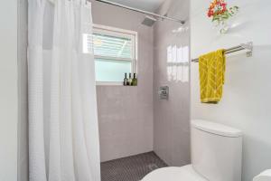 a bathroom with a white shower curtain and a toilet at The Avocado Door - A Mid-Century Modern Gem ~ Near SoCo ~ Fenced yard ~ Corner lot in Austin