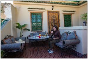 a woman sitting at a table on a patio at Riad Fés blida in Fez
